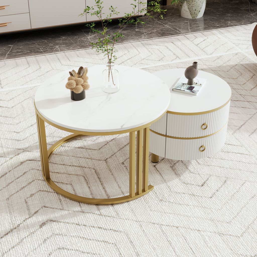 A white marble-patterned round coffee table with a gold base is next to a cylindrical white side table with two drawers and gold accents. The tables are on a patterned rug in a living room setting.