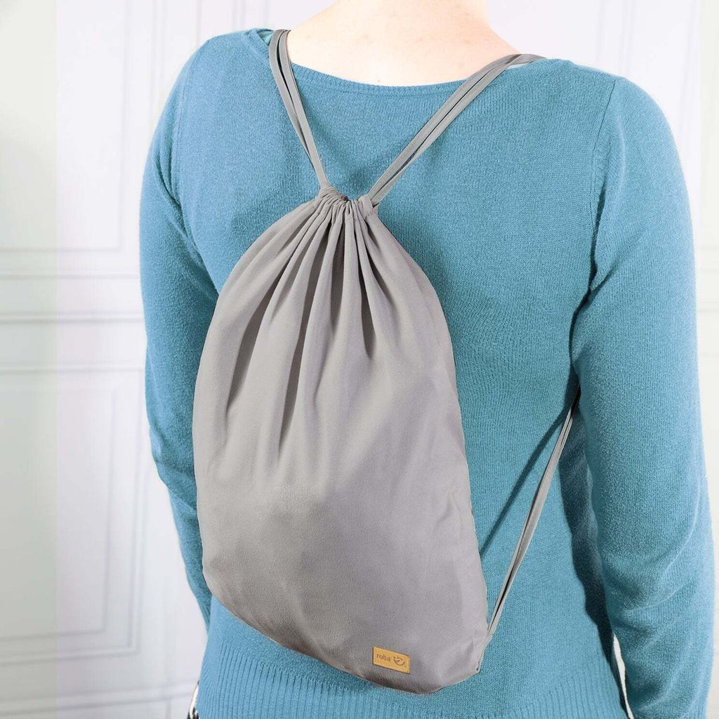 A person wearing a blue sweater and a gray drawstring backpack.