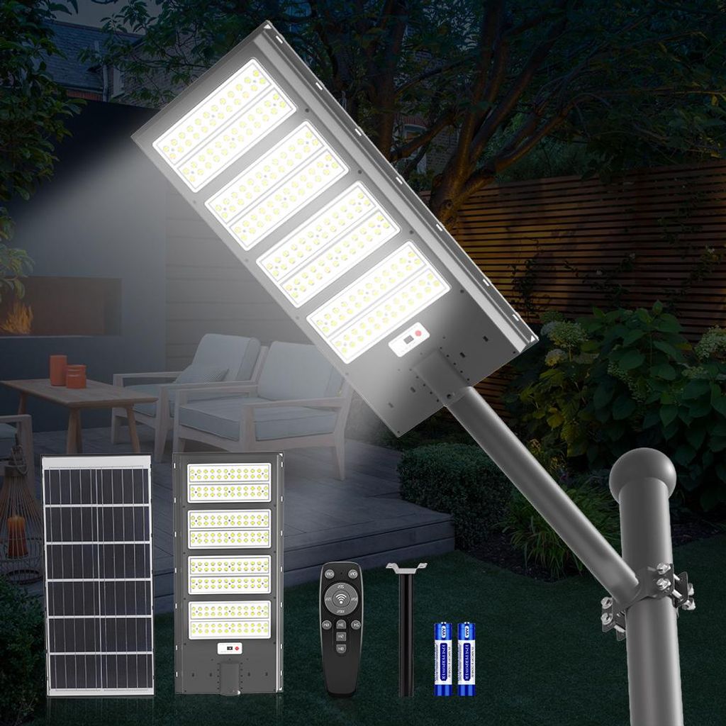 A solar street light and its components are displayed in a garden setting at dusk.