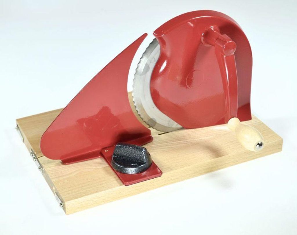 A red manual slicer is placed on a wooden board against a white background.