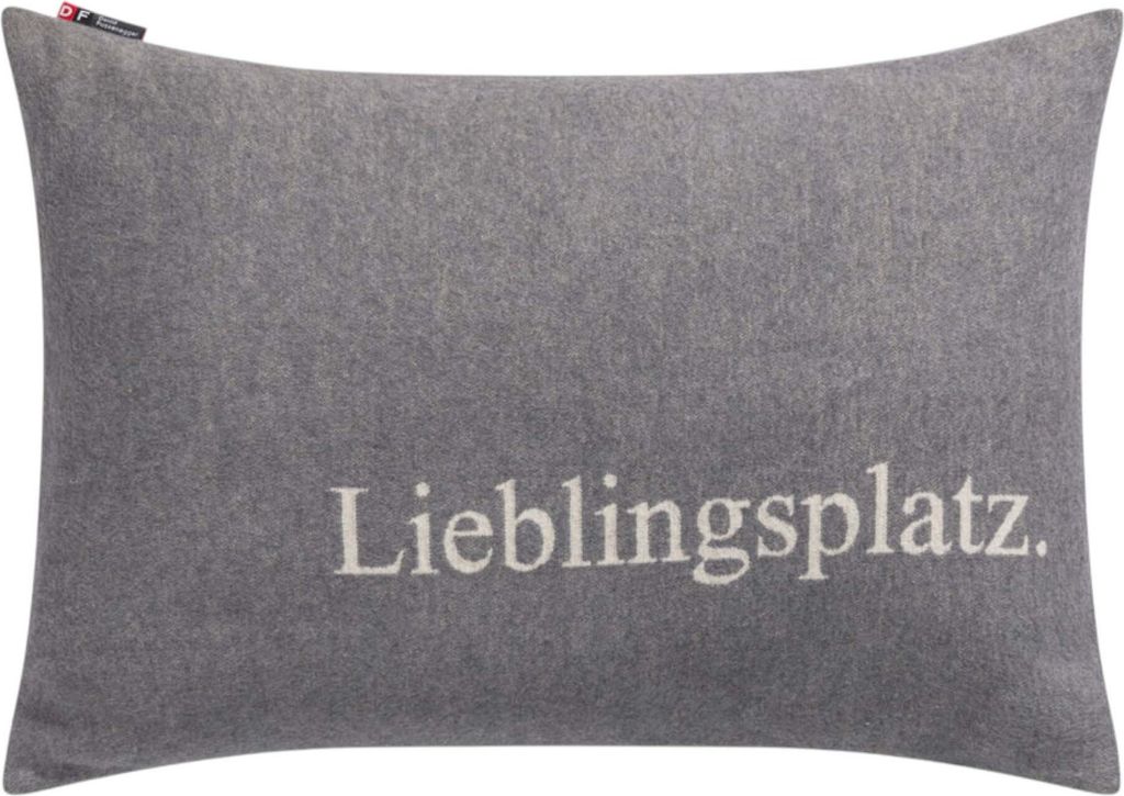 A gray pillow with the word "Lieblingsplatz" embroidered on it.
