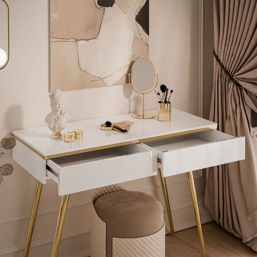 A white vanity table with gold legs and open drawers, decorated with a bust, makeup brushes, and a mirror. A stool is placed in front of the table.