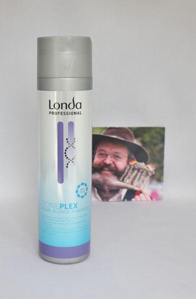 A bottle of Londa Professional Toneplex Pearl Blonde Shampoo is placed next to a framed photograph of a man.