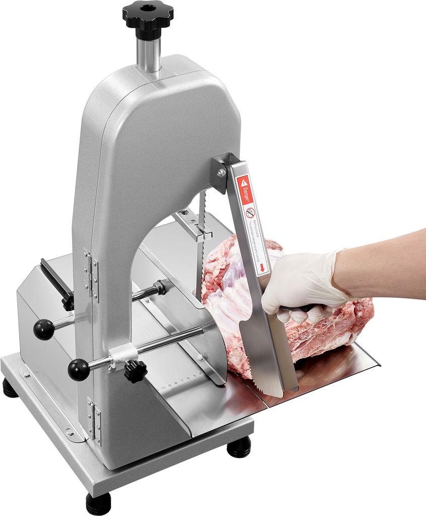 A person wearing white gloves is using a commercial electric meat band saw to cut a large piece of meat.