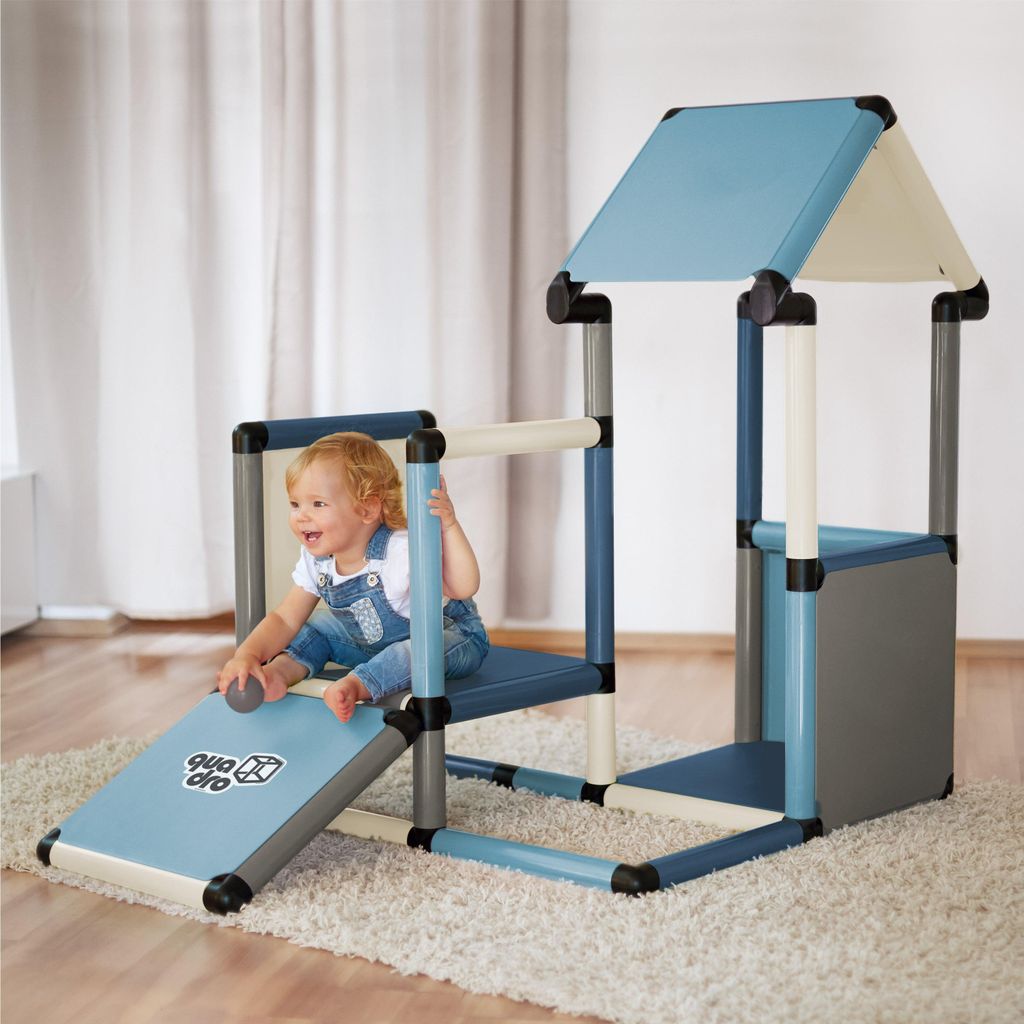 A baby is playing on a modular playhouse structure indoors.