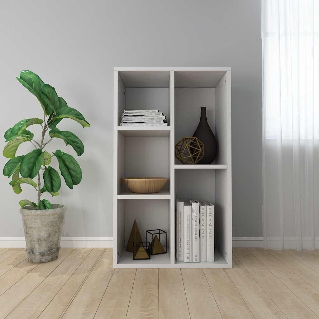 A white bookshelf with various decorative items and books on it, placed next to a potted plant in a room with light gray walls and a wooden floor.