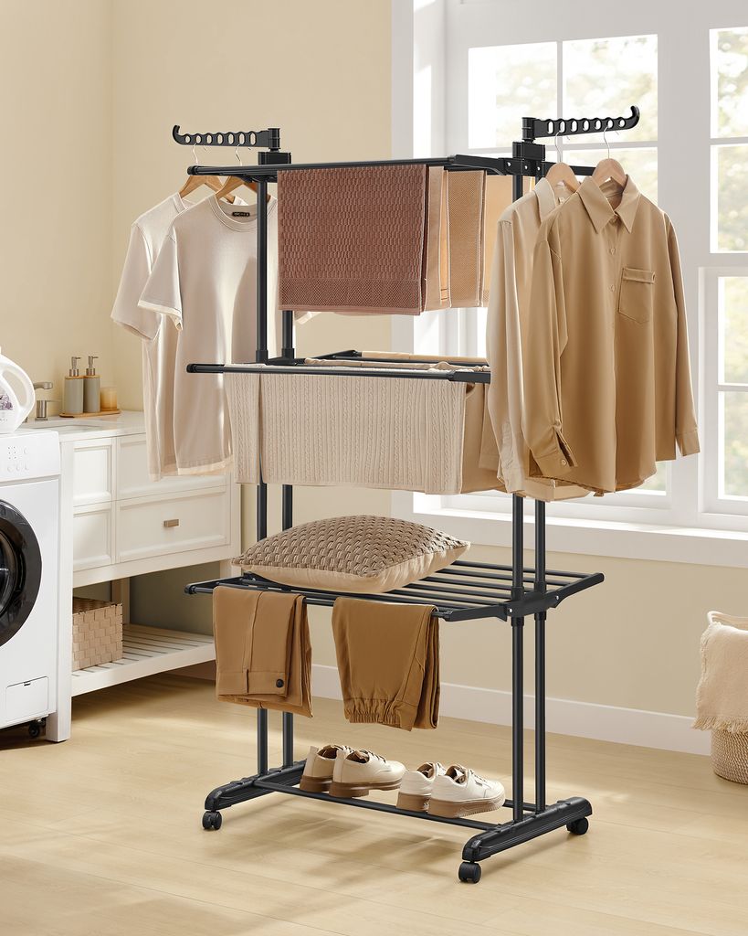 A laundry drying rack with clothes and accessories in a room with a washing machine and window.