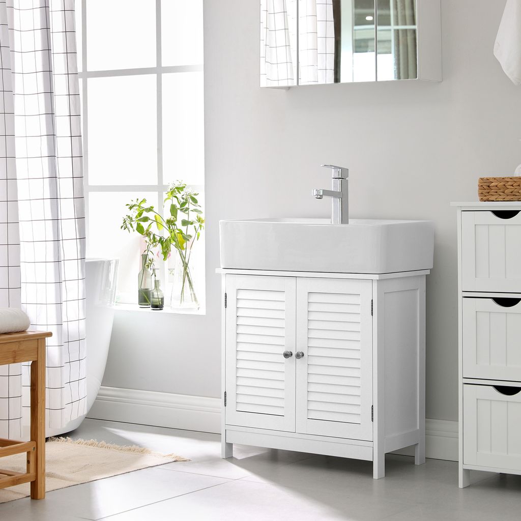 A white bathroom vanity with a sink and faucet, next to a window with a checkered curtain and a bathtub.