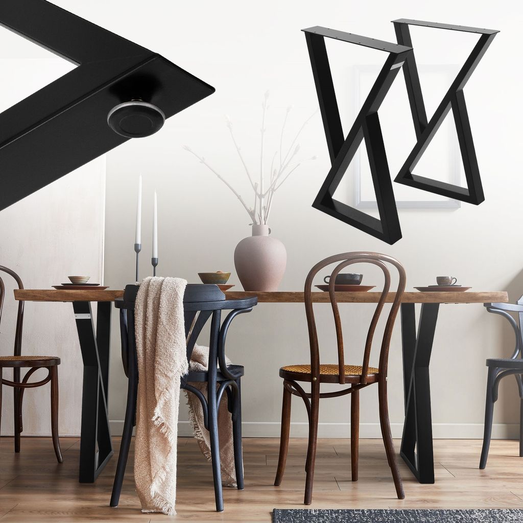 A dining table with black metal legs and chairs, set with plates and candles.