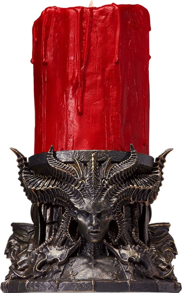 A red candle in a decorative, dark-colored holder with a demonic or gothic design.
