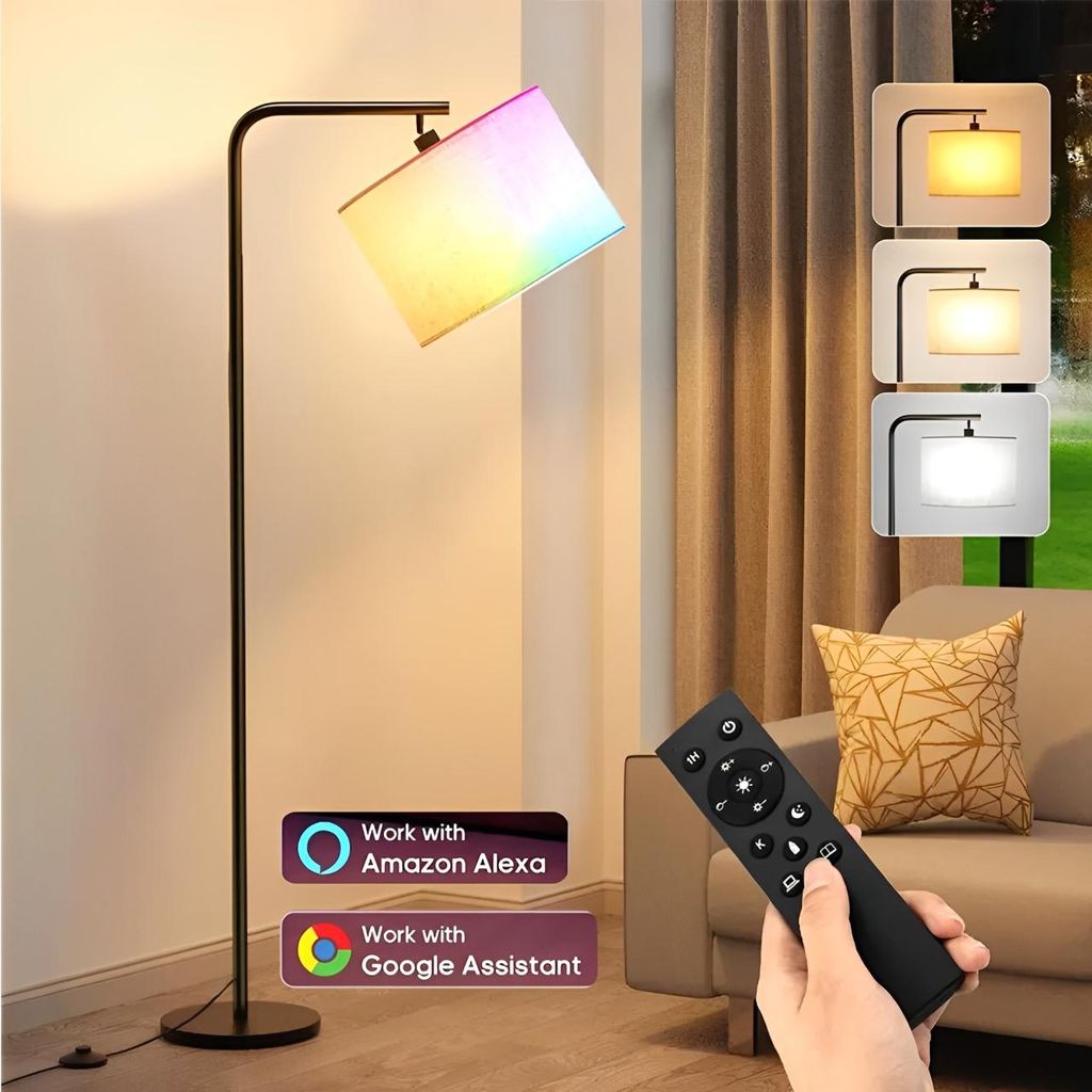 A modern RGB floor lamp with a fabric shade displaying multiple colors, shown in a living room setting next to a sofa. A remote control is held in a person's hand.