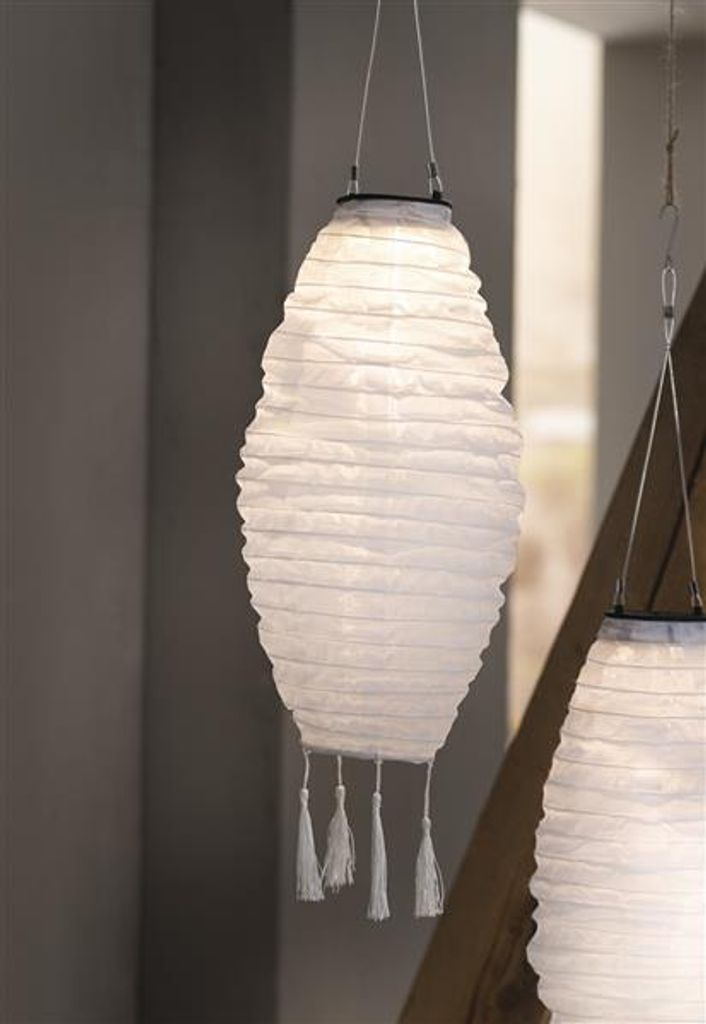 Two white paper lanterns hang indoors, one in the foreground and another partially visible in the background.