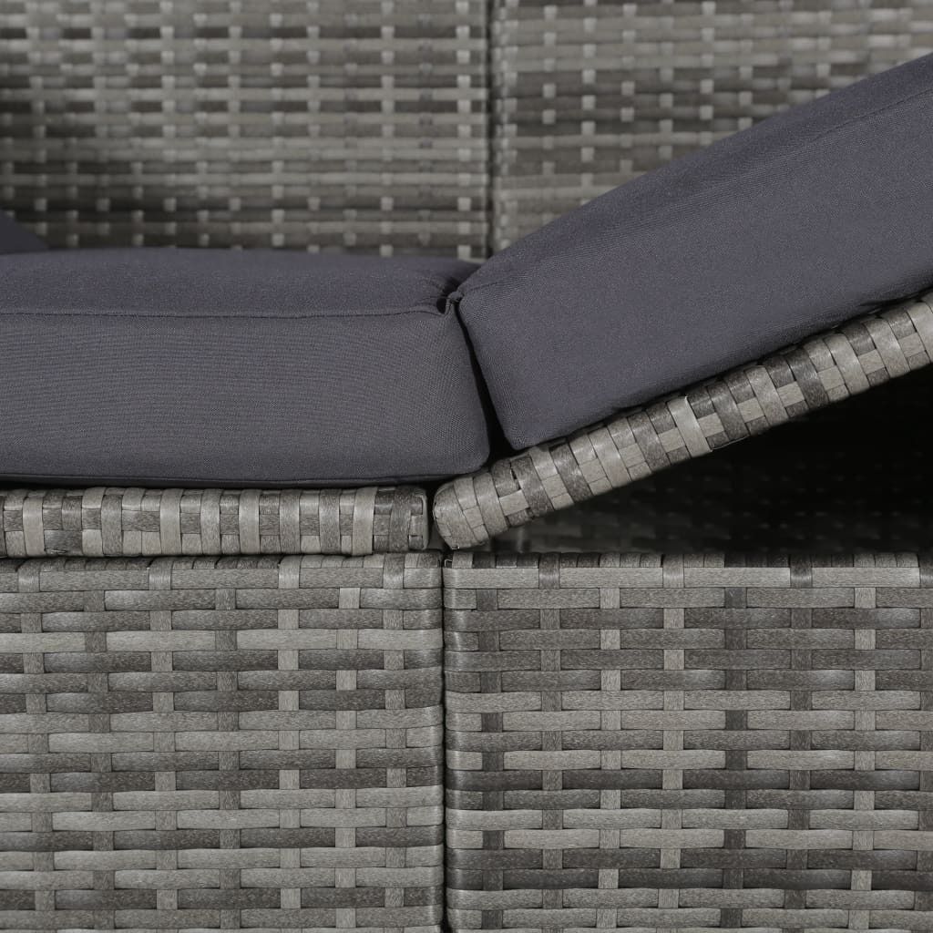 A close-up view of a gray rattan garden bed with dark gray cushions.