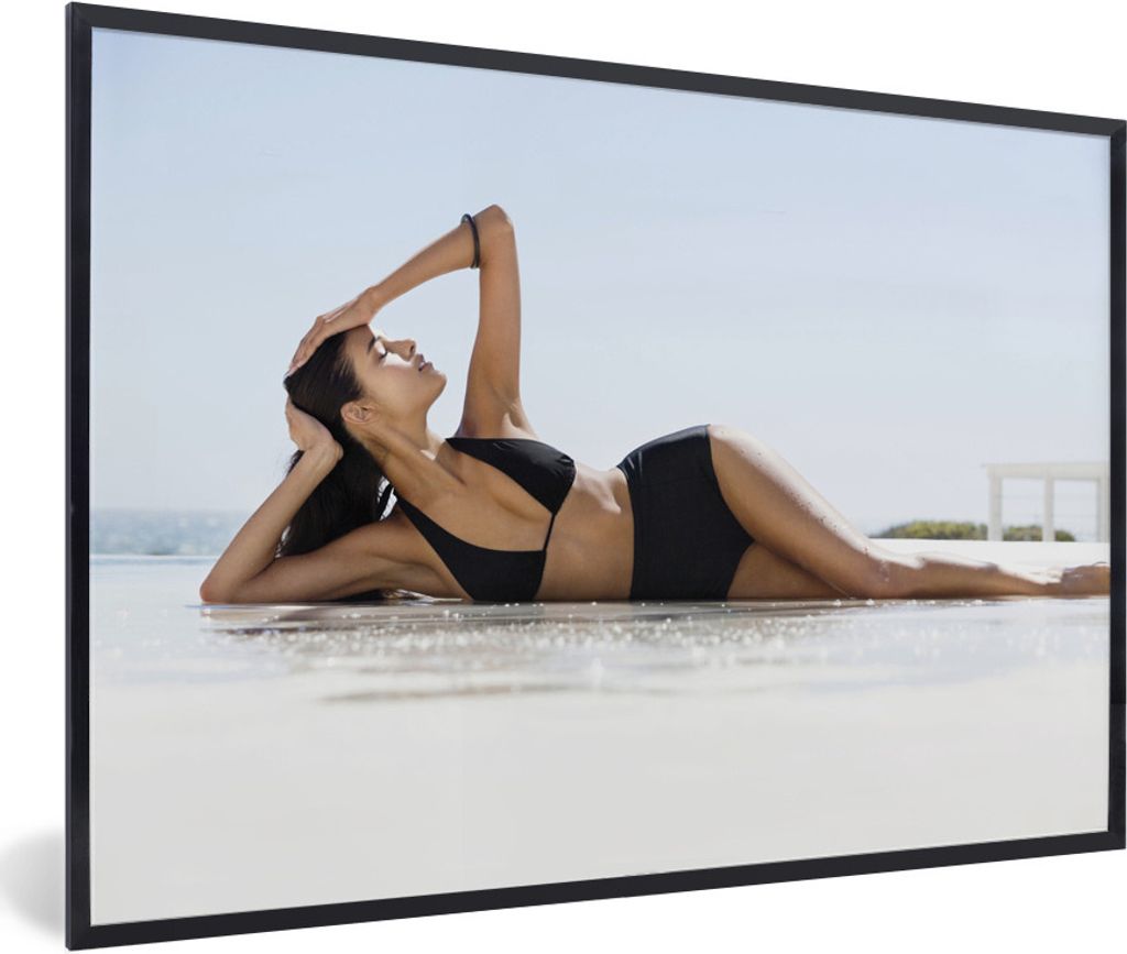 MuchoWow Gerahmtes Poster Eine Frau in einem schwarzen Bikini posiert am Strand 30x20 cm - Poster mit Schwarzem Bilderrahmen Wandposter Rahmen Fo...