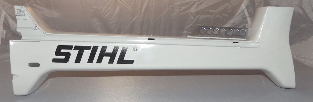 A white Stihl part with the Stihl logo on it, lying on a light gray surface.