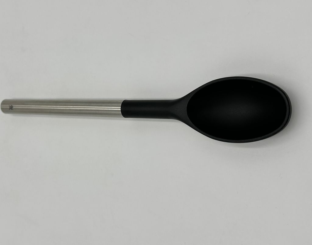 A single black and silver spoon is laid horizontally on a plain white background.