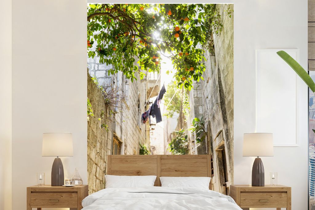 MuchoWow Fototapete für Wohnzimmer oder Schlafzimmer Wandtapete Vinyl Motivtapete Ein Orangenbaum in einer engen Gasse - 225x350 cm - Schlafzimm...