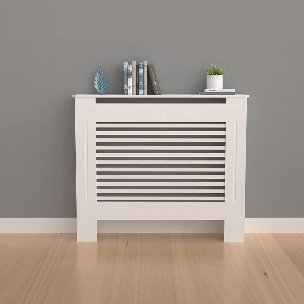 A white radiator cover with horizontal slats is placed against a gray wall and on a light wood floor.