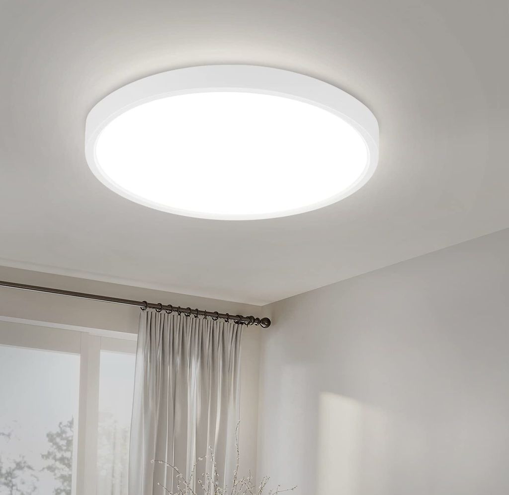 A white, circular LED ceiling light is mounted on a white ceiling.