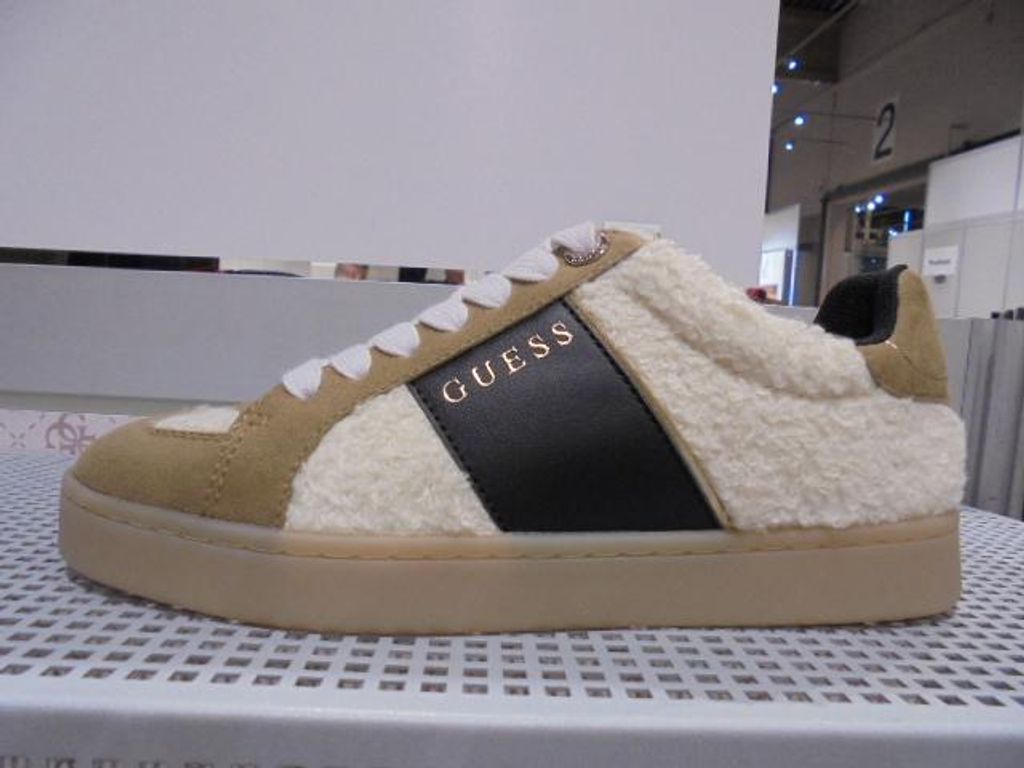 A single Guess sneaker is displayed on a white grid surface.