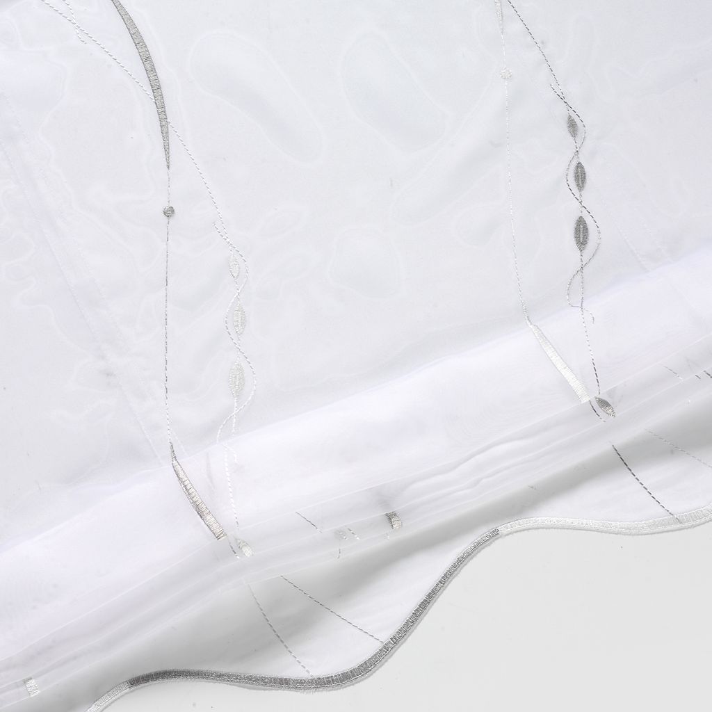 A close-up view of a white and silver roller blind, showing its textured fabric and decorative stitching.