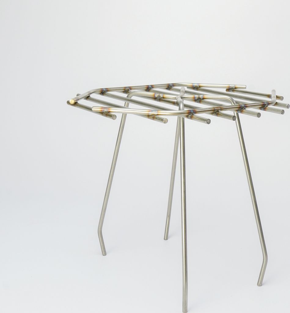 A stainless steel grate with three legs, presented against a white background.
