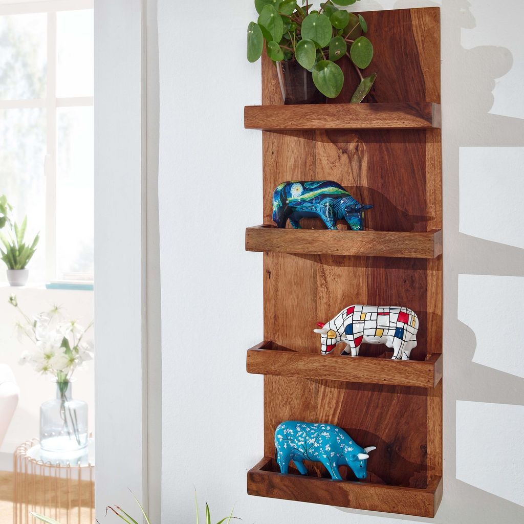 A wooden wall shelf with decorative figurines and a plant.