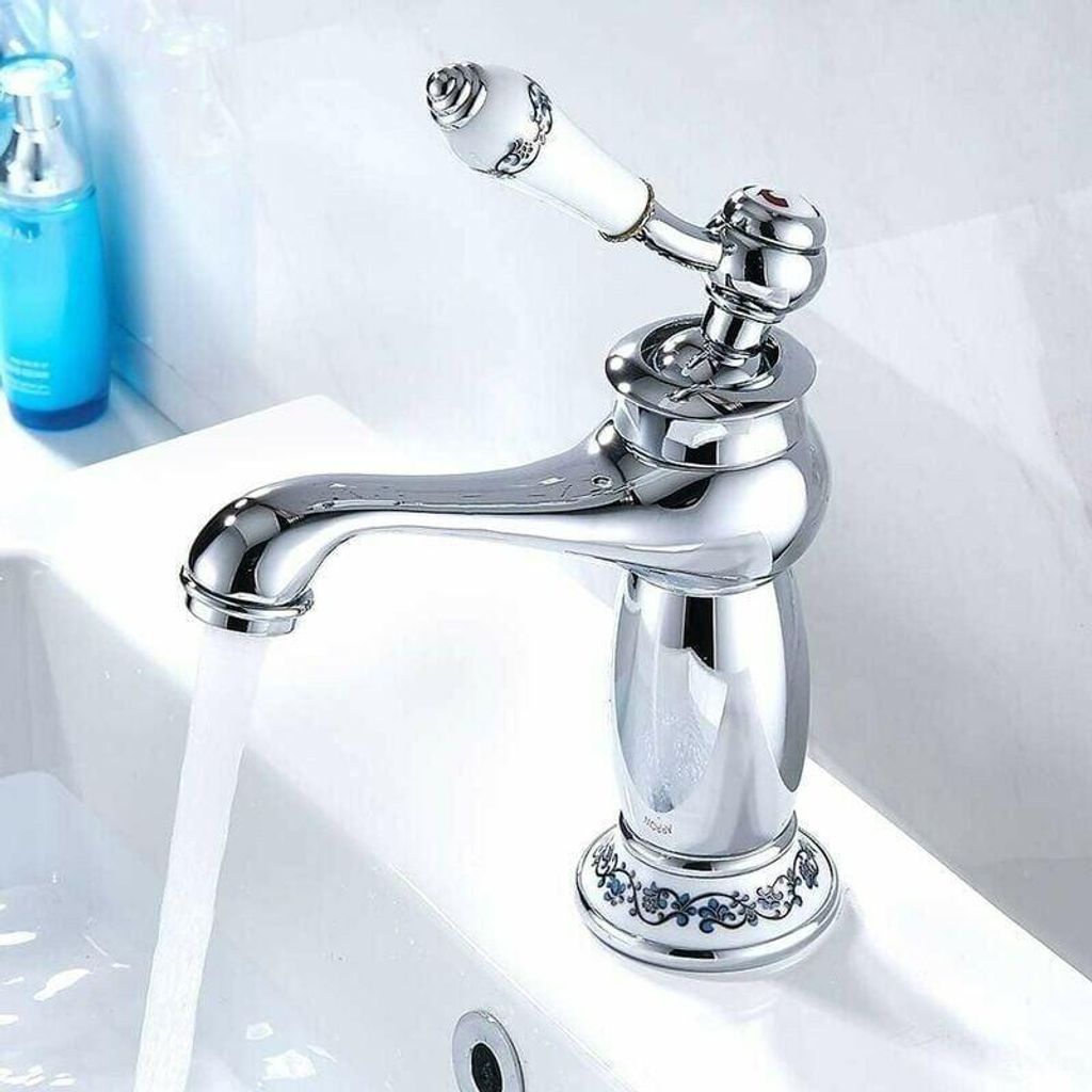 A close-up shot of a chrome faucet with a white ceramic handle, dispensing water into a white sink.