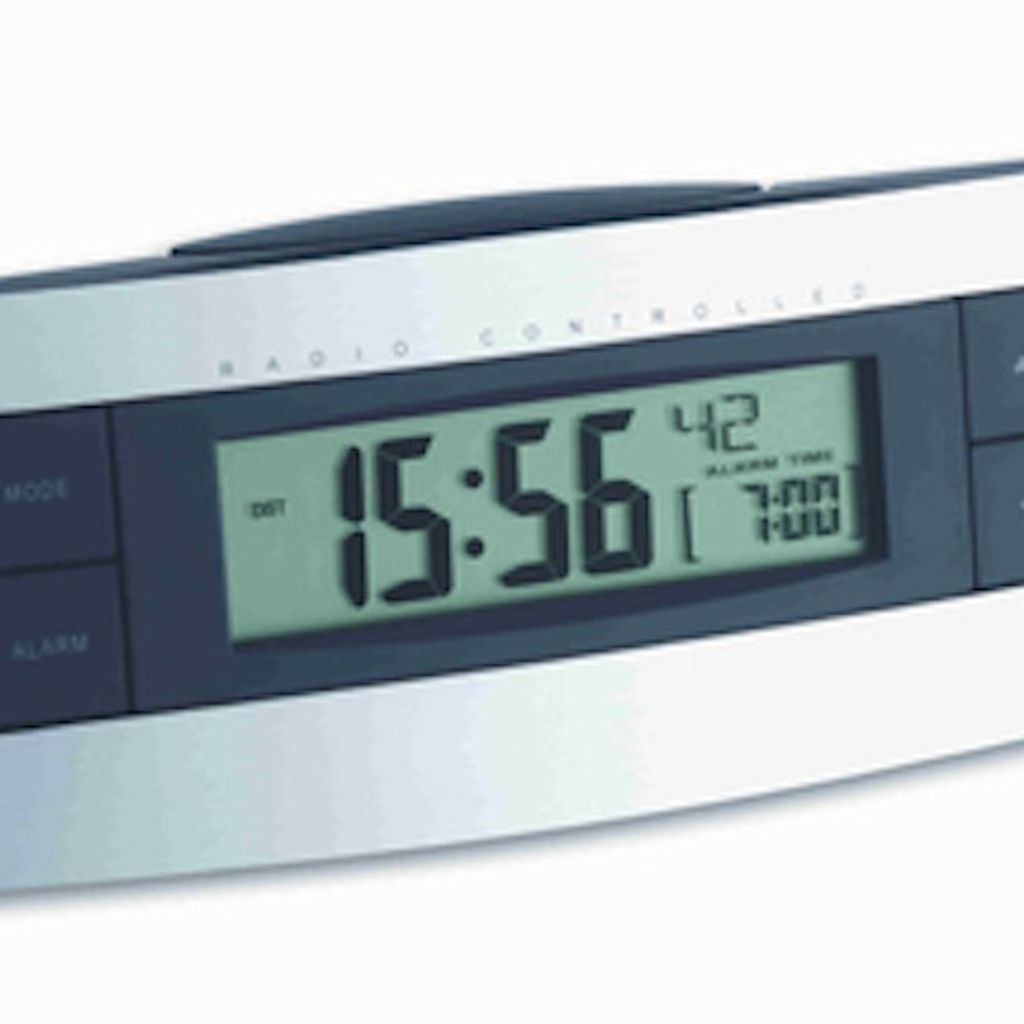 A close-up shot of a digital alarm clock displaying the time and alarm settings.
