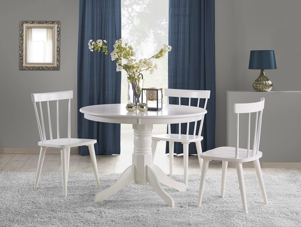 A white round dining table with three white chairs in a dining room setting.