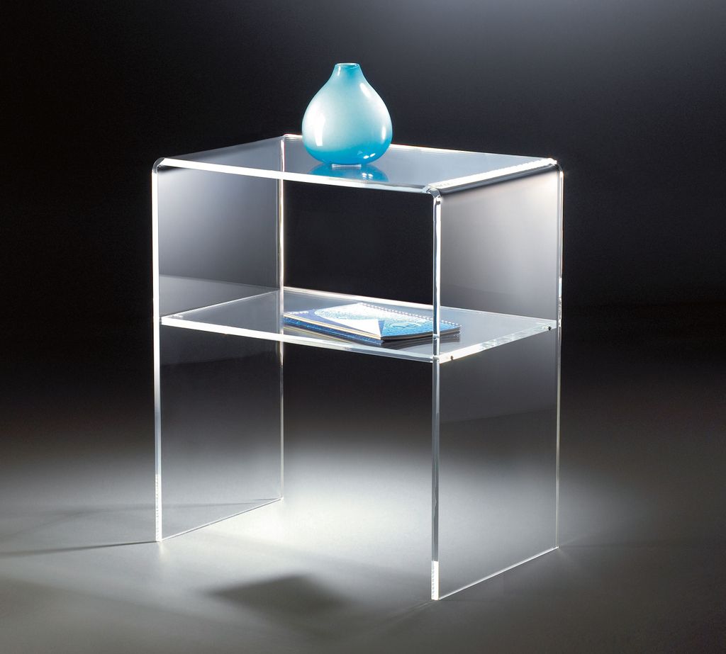 A clear acrylic side table with a blue vase on top and a book on the shelf.