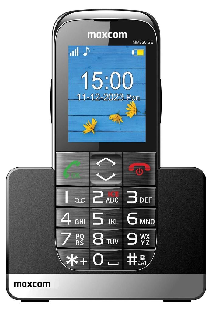A black Maxcom MM720 SE mobile phone is shown in its charging dock.