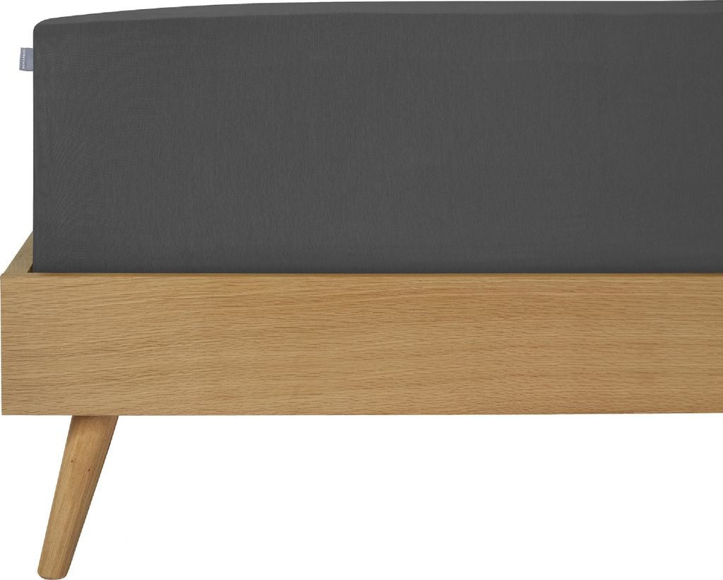 A close-up view of a dark gray fitted sheet on a wooden bed frame with angled legs.