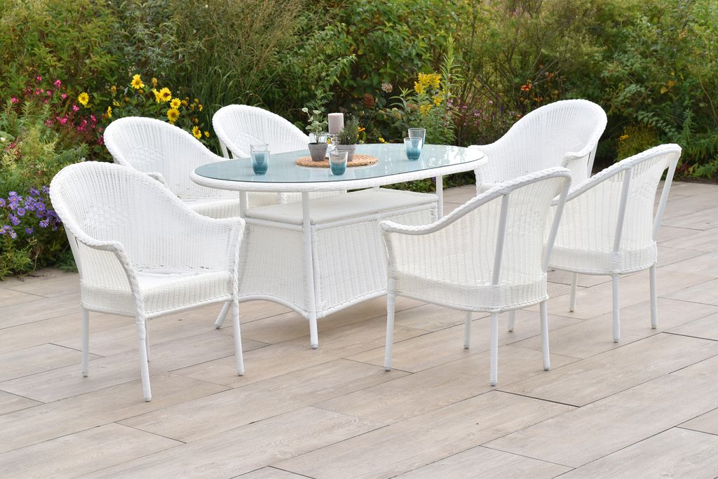 An outdoor dining set with chairs and a table on a patio, surrounded by plants and flowers.