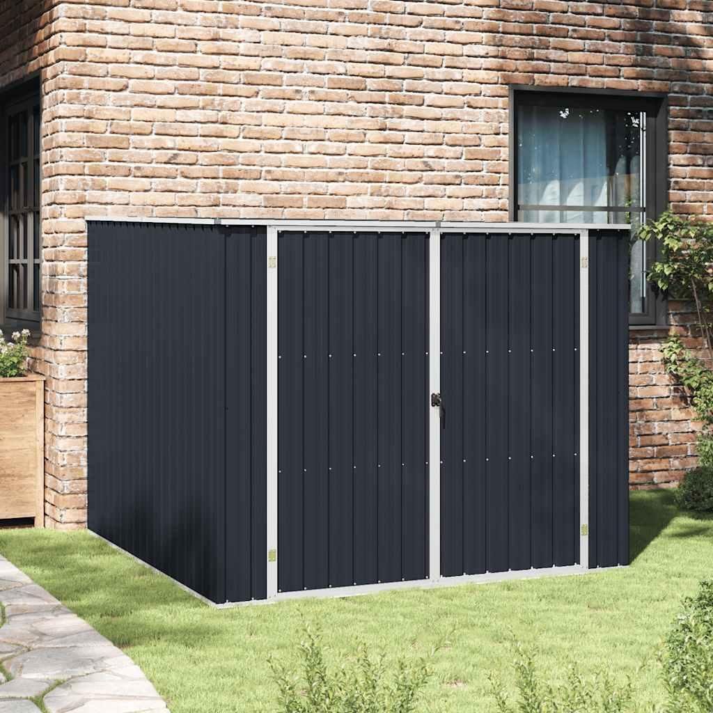 A dark gray metal storage shed is placed on a grassy lawn next to a brick building.