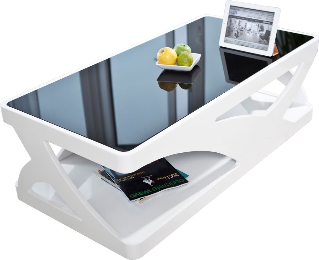 A modern white coffee table with a black glass top, decorated with a small bowl of fruit and a tablet device.
