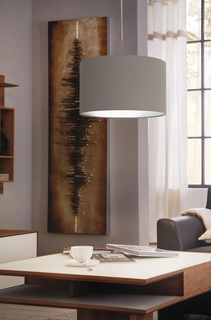 A living room scene with a pendant lamp, artwork, and a coffee table.