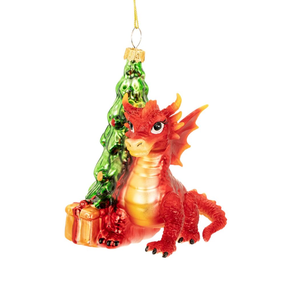 A red dragon ornament sits next to a green Christmas tree and a wrapped gift.