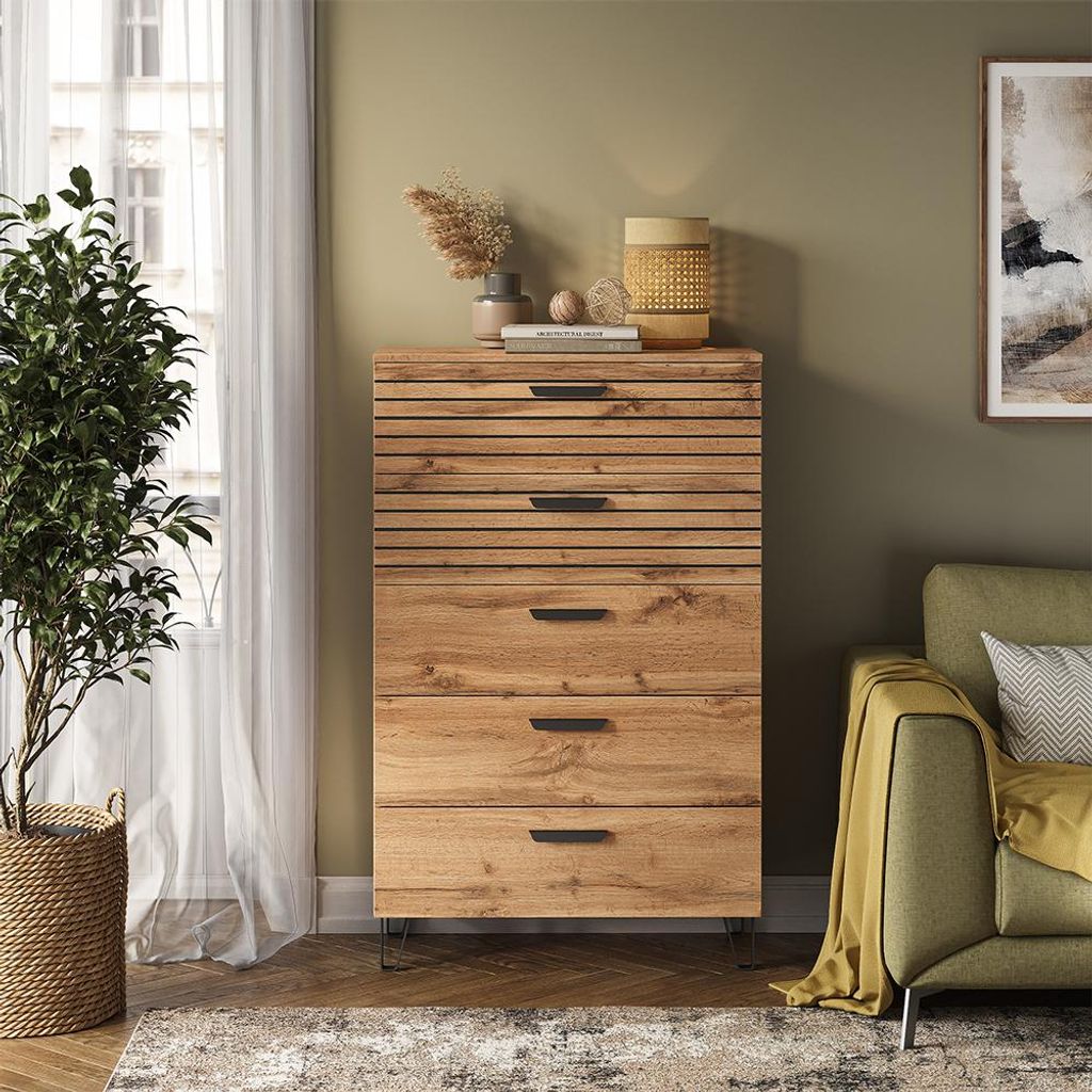 A chest of drawers in a living room setting, next to a sofa and a plant.