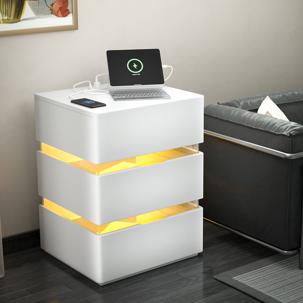 A white nightstand with illuminated drawers is placed next to a dark sofa in a room.