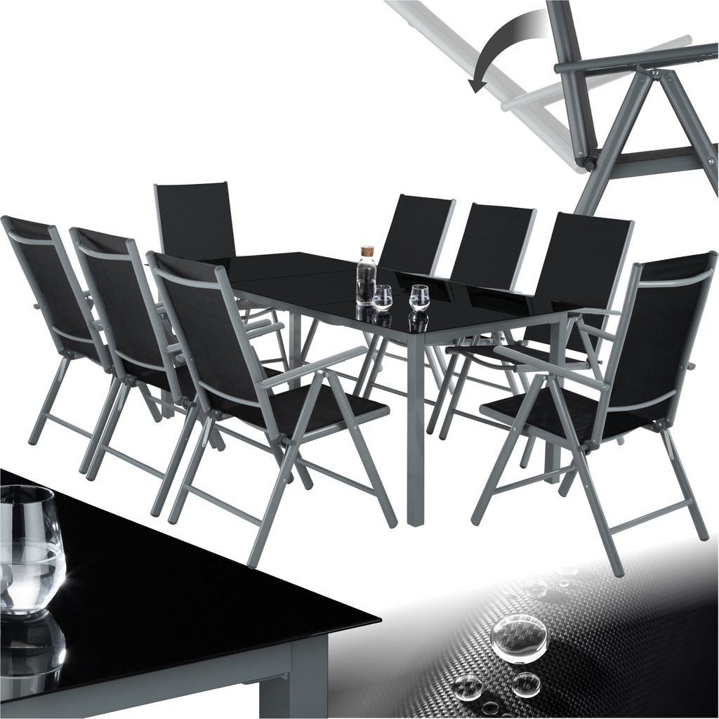 A dining set with a black glass table and eight black chairs with aluminum frames, presented on a white background with a subtle graphic overlay at the bottom.