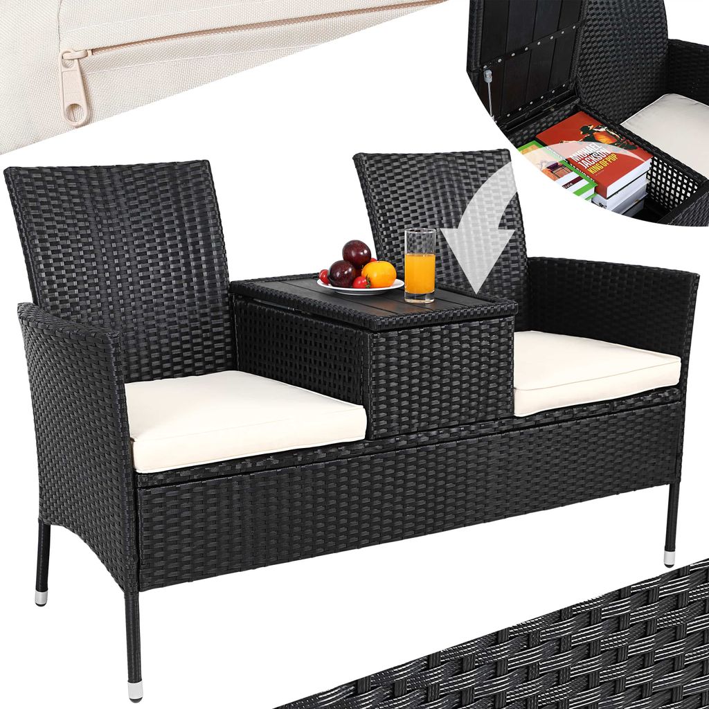 A black rattan garden bench with white cushions and a central table. The table has a glass of orange juice and fruit on it. An inset shows the storage compartment of the table open with books inside.