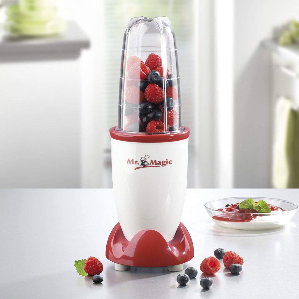 A Mr. Magic blender filled with berries sits on a white countertop, with a bowl of yogurt and berries in the background.