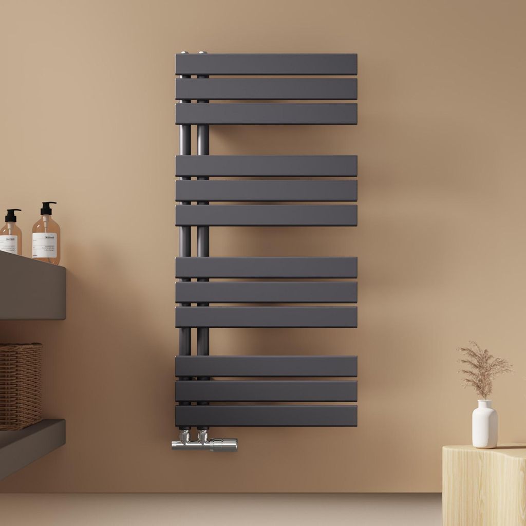 A modern anthracite radiator mounted on a light brown wall in a bathroom setting.