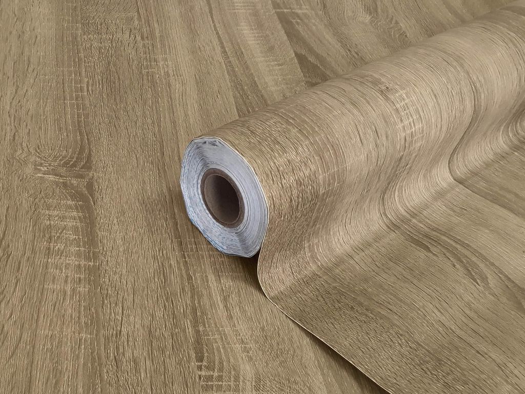 A roll of self-adhesive wood-effect film, designed to mimic the look of oak wood.