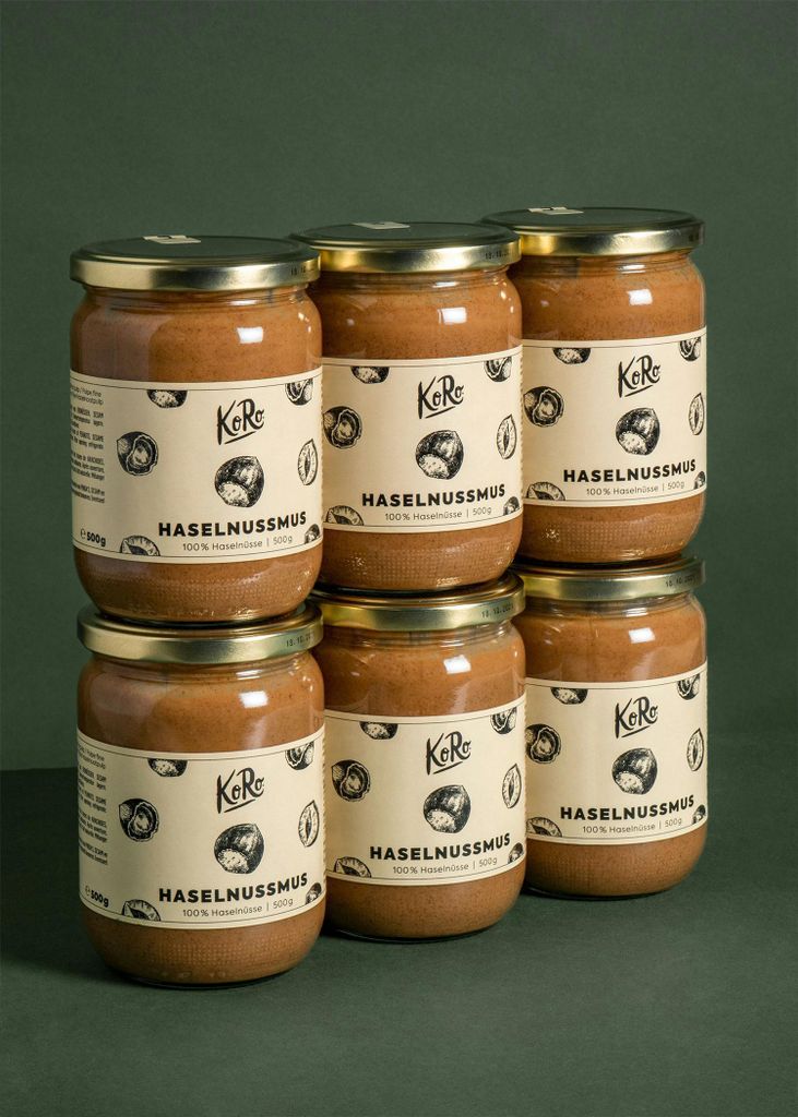 Six jars of hazelnut spread stacked in two rows against a dark green background.