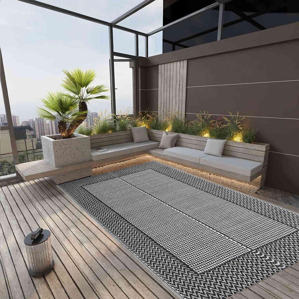 An outdoor patio or balcony with a rug, seating, and plants.