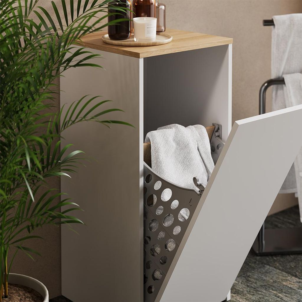 A bathroom cabinet with a laundry basket inside, next to a potted plant.