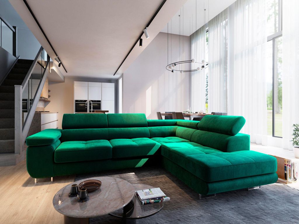 A spacious, modern living room with a large green sectional sofa as the focal point. The room features a staircase, dining area, and large windows with sheer curtains.