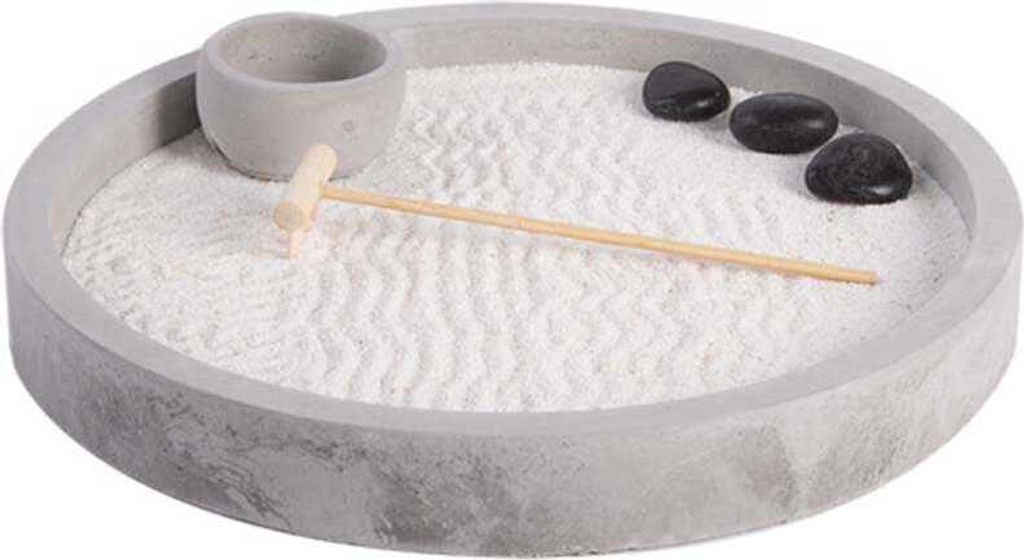A miniature zen garden with white sand, a small grey pot, a wooden rake, and three black stones.